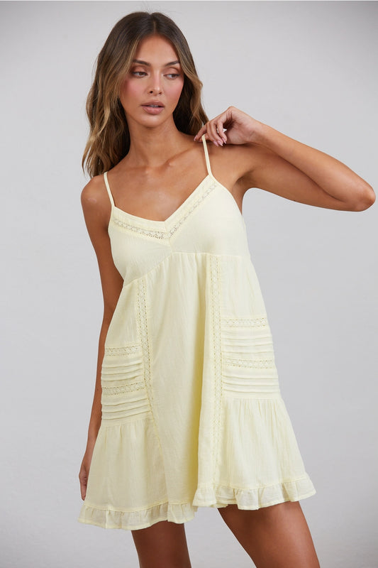 Woman wearing a light yellow dress against a plain background
