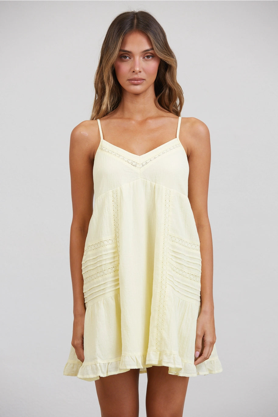 Woman wearing a light yellow dress against a plain background