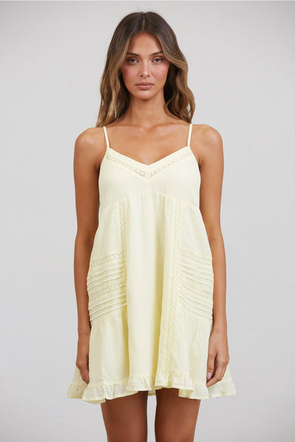 Woman wearing a light yellow dress against a plain background