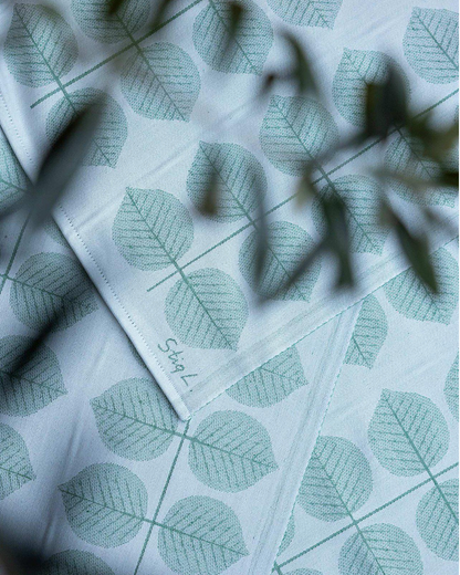 Fabric with leaf pattern and Stig. L branding on a light blue background