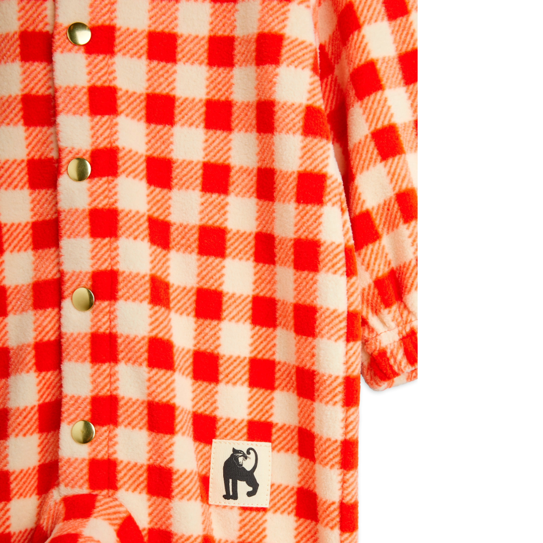 Close-up of a red and white checkered shirt with a Jaguar brand logo on a white background