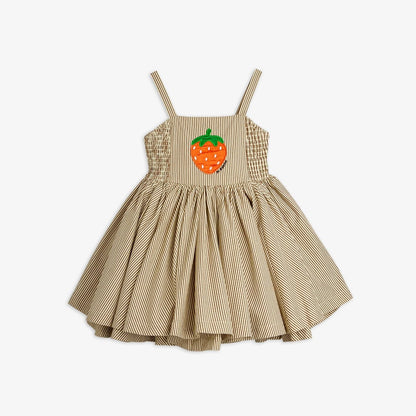 A toddler girl's sleeveless dress with thin shoulder straps, featuring a smocked bodice, a flared gathered skirt, and an orange strawberry applique on the chest, shown against a plain light gray background.