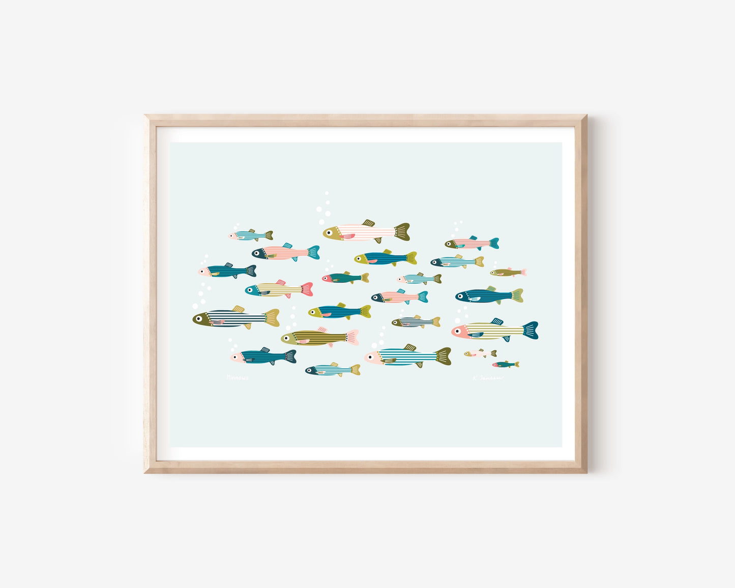A framed art print featuring a colorful illustration of various stylized fish swimming in a light blue water scene, set in a natural wood frame against a white wall.