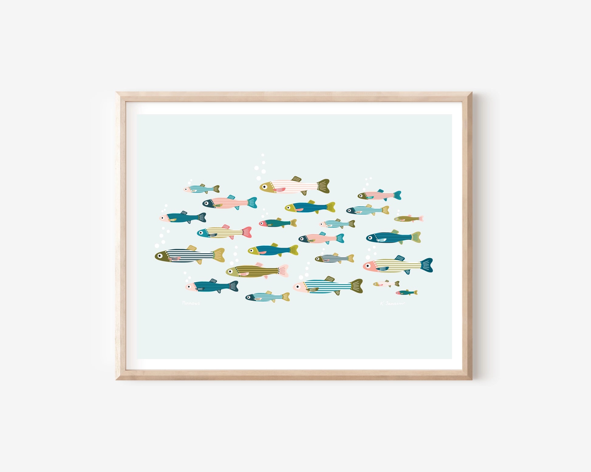 A framed art print featuring a colorful illustration of various stylized fish swimming in a light blue water scene, set in a natural wood frame against a white wall.