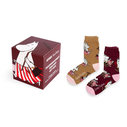 A pair of Moomin-themed socks displayed next to their branded gift box. The socks feature character prints in brown, burgundy, and pink, while the box is dark red with white and red illustrations.