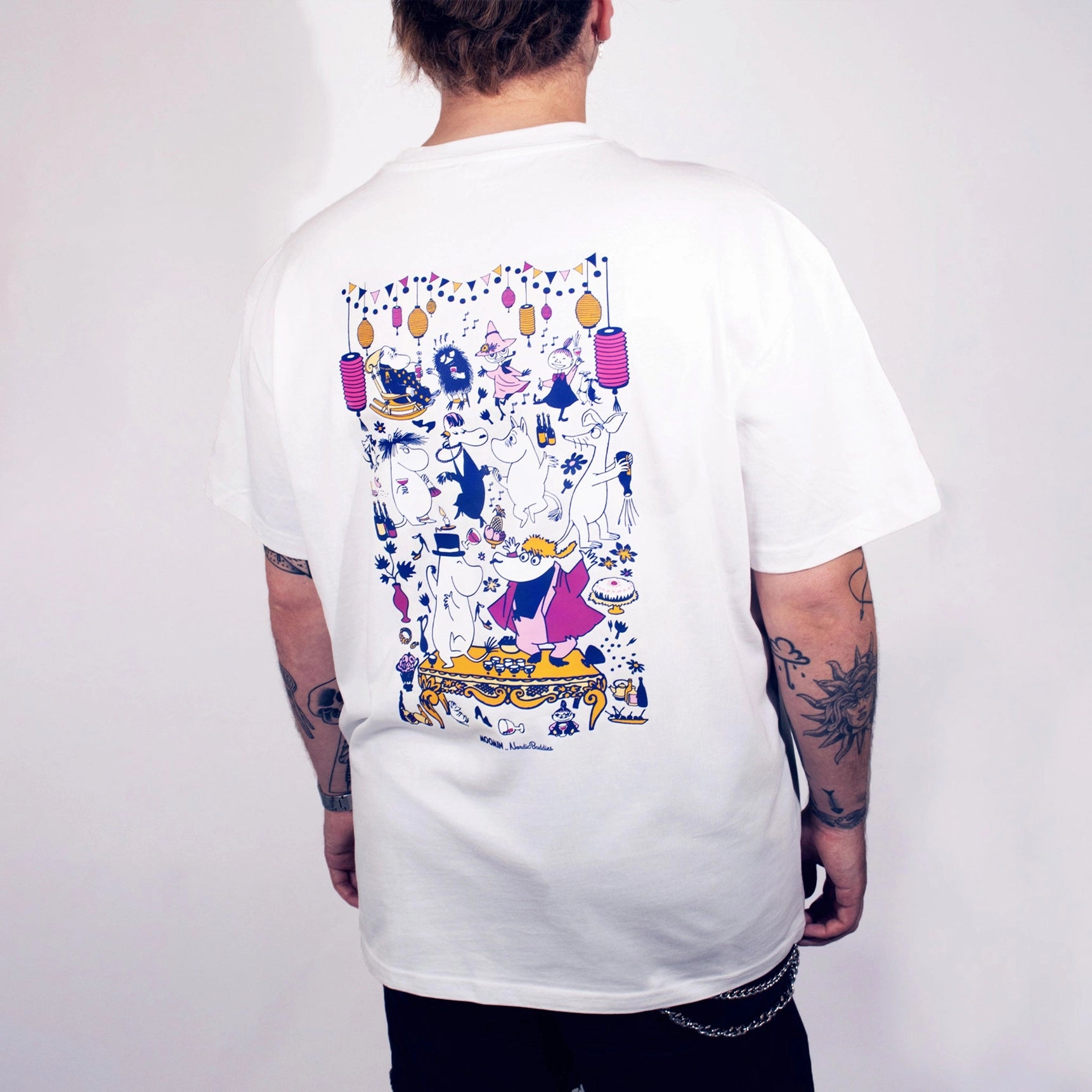 Person wearing a white t-shirt with colorful graphic design on the back against a plain background