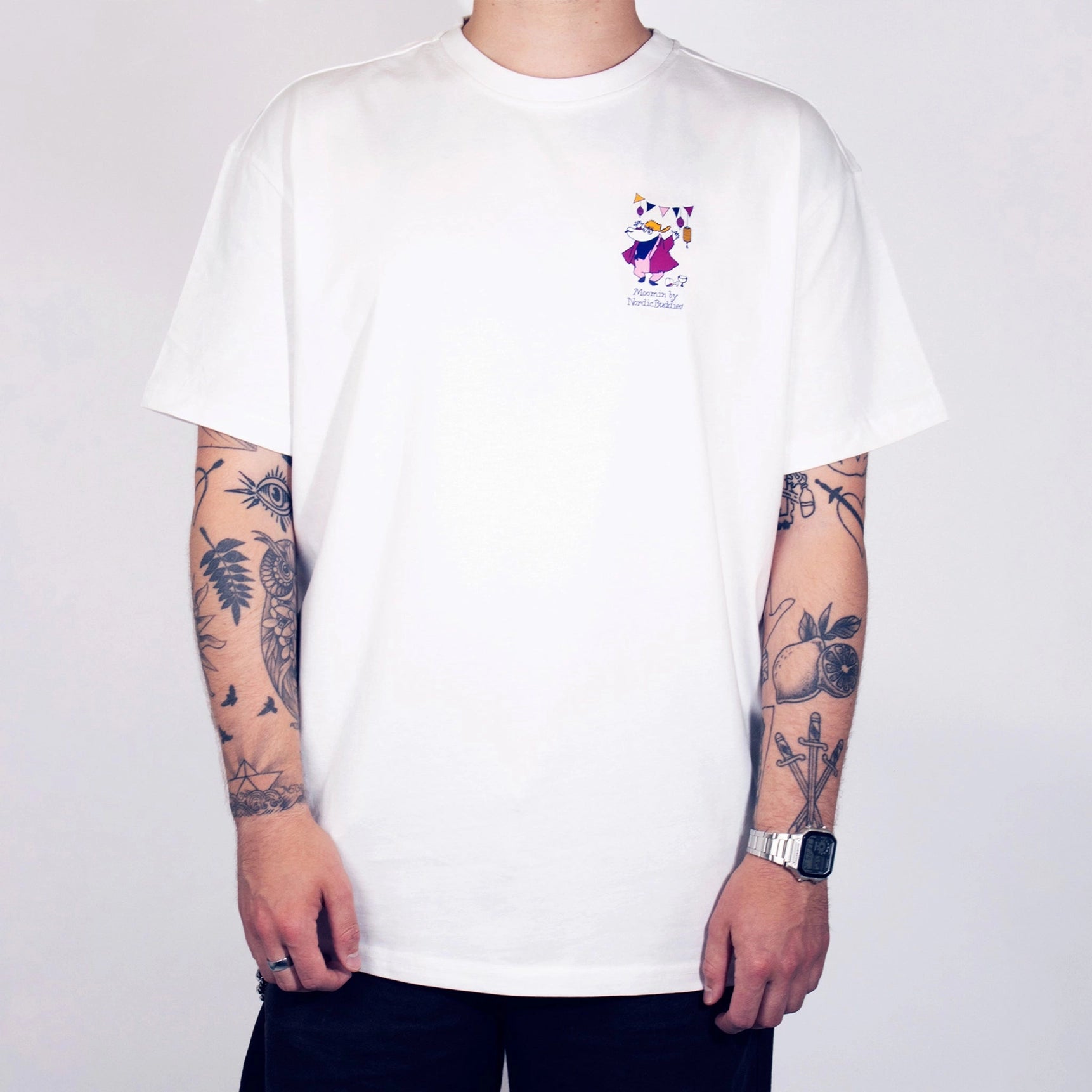 Person wearing a white t-shirt with a small logo on a plain background