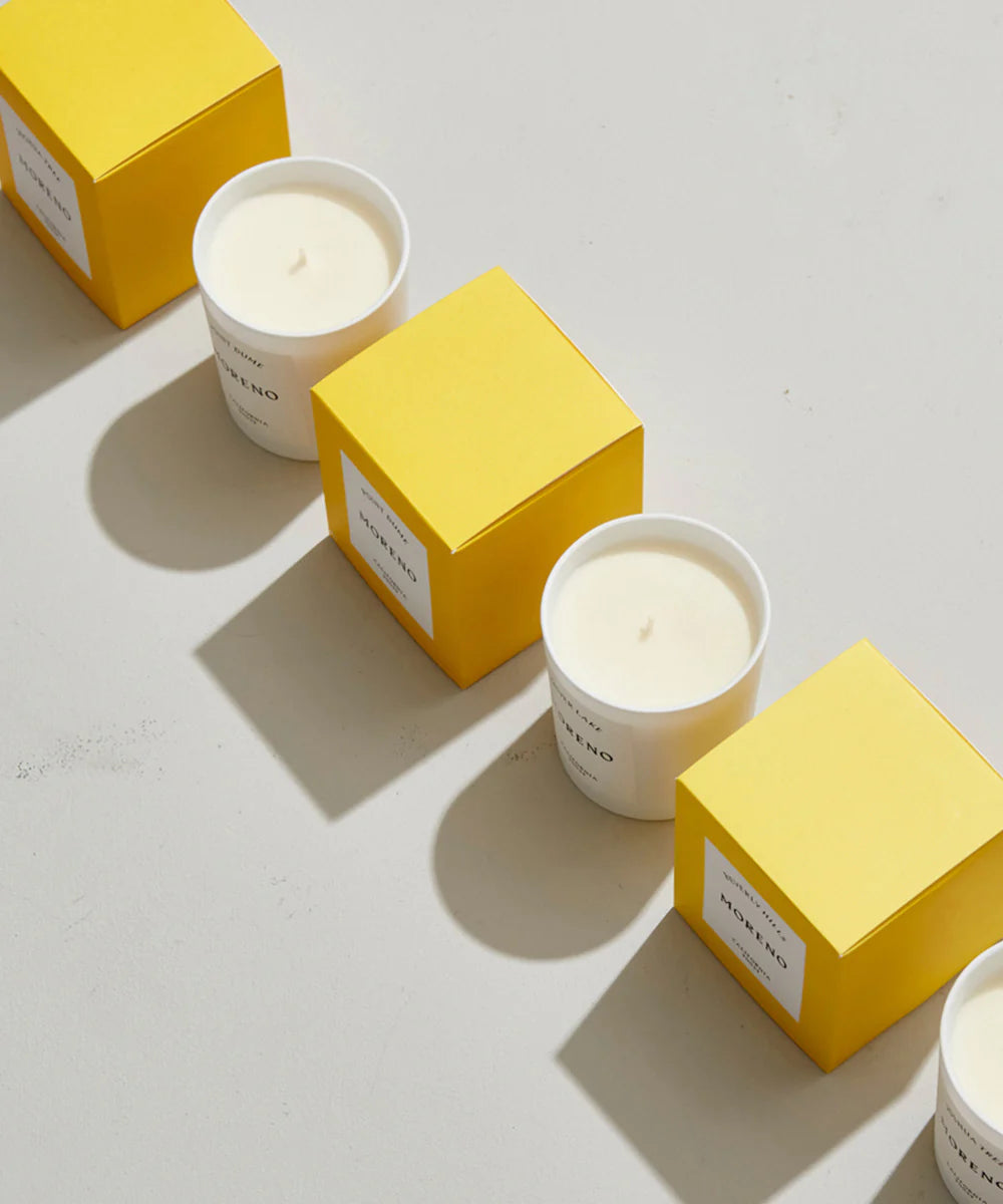 White candles with yellow boxes on a light gray background made in the South of France and inspired by Los Angeles areas and cities. They make great gifts and are so elegant and modern. 