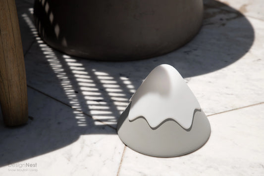 White ceramic mountain-shaped object on a light surface with shadows 