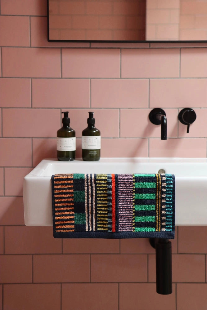 Colorful face towel on white sink with pink tiles
