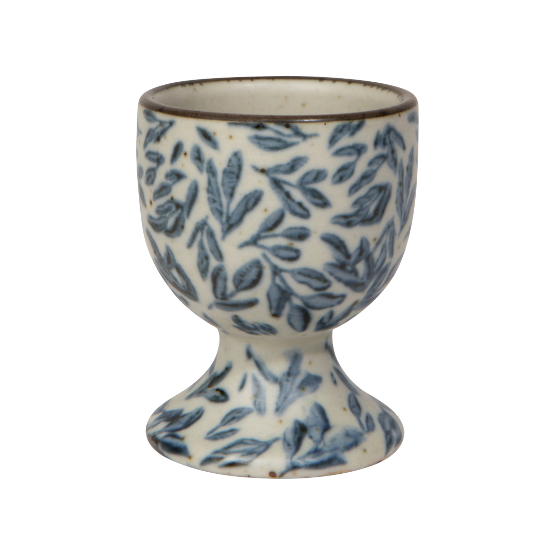 Ceramic egg cup with blue leaf pattern on a white background. Capture the essence of water, air, earth, and fire with the Myrtle Egg Holder from the Element collection. It soothes, revives, grounds and ignites— awakening our natural connection to the elements.