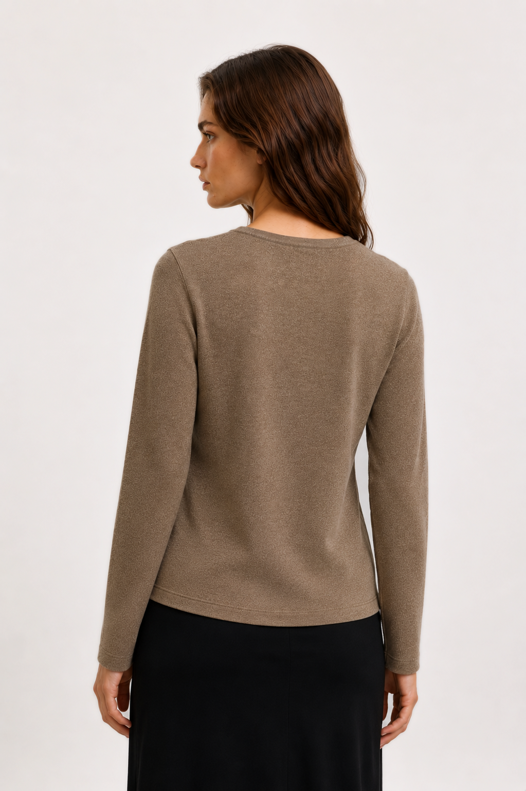 A woman shown from the back wearing a long-sleeve knit sweater in taupe brown and a black skirt, photographed against a clean white studio background.