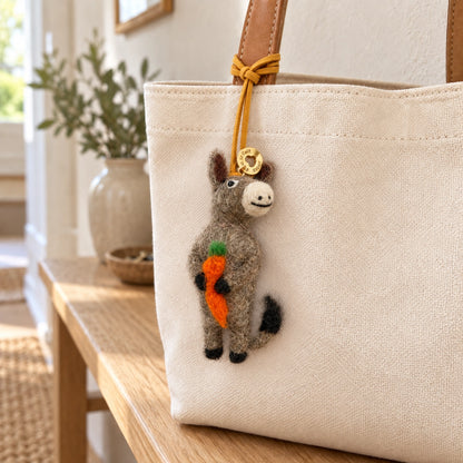 Donkey Bag charm on Beige tote bag on wooden bench