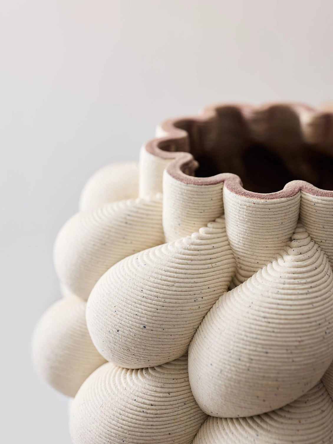 Close-up of a textured ceramic bowl with a scalloped edge on a light background