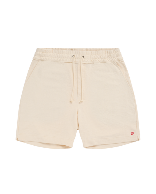 Beige shorts with a small red logo on a white background