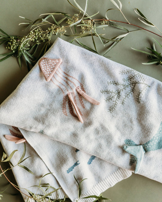 Textured fabric with embroidered designs and a pink hair clip on a green background