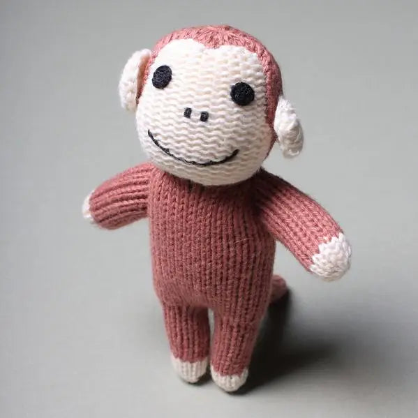 Knitted monkey toy with pink and white colors on a gray background