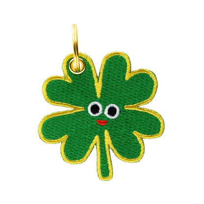 Green four-leaf clover charm with a face on a white background