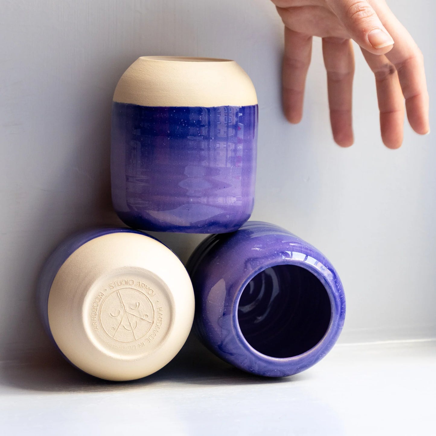 Three ceramic jars with blue and beige colors on a white surface.