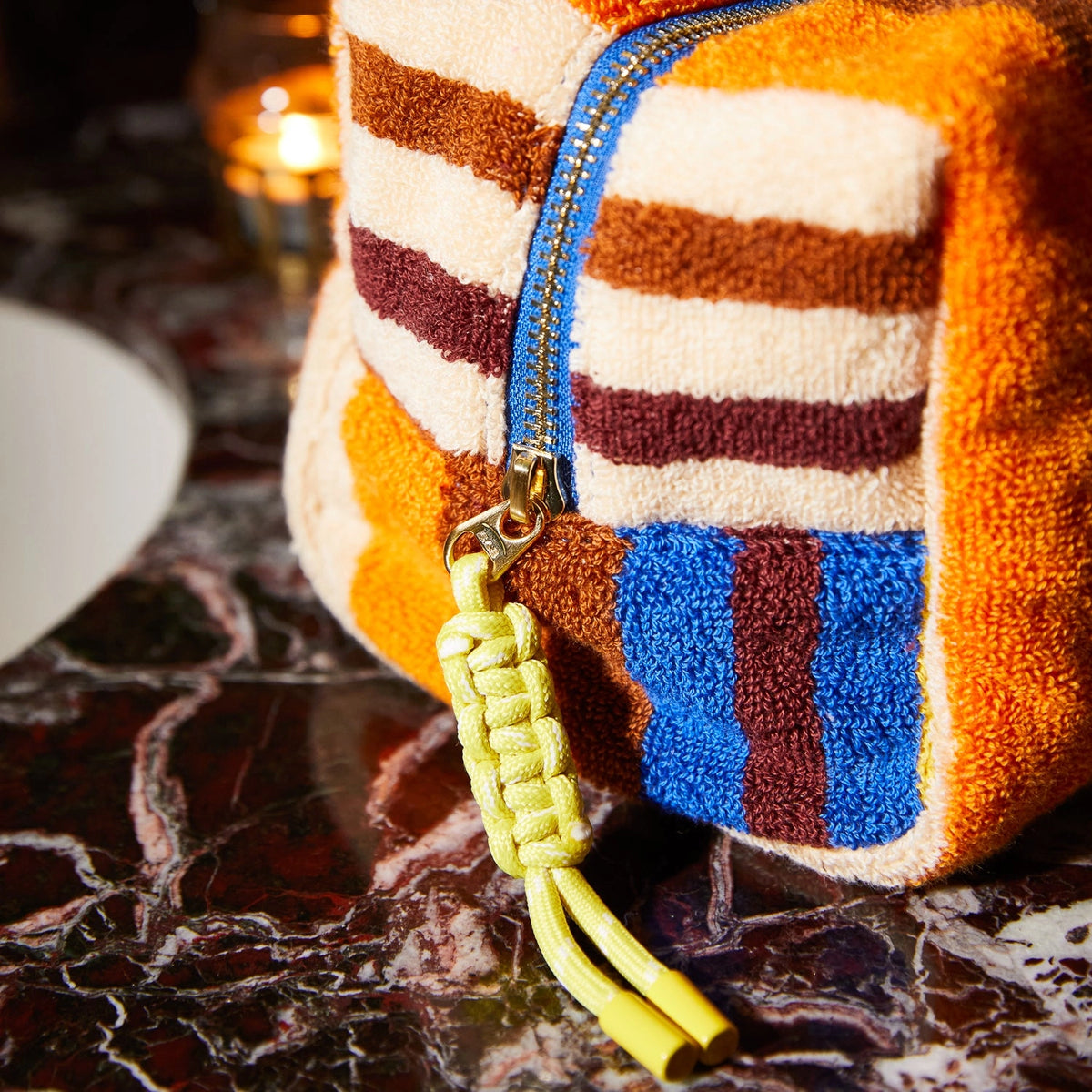 Colorful textured pouch with a yellow strap on a dark surface