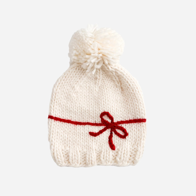 A fun Holiday hat to celebration the biggest gifts in life. Features a yarn Red bow and Cream yarn pom. Pair this hat with the matching sweater or a coordinating cardigan.