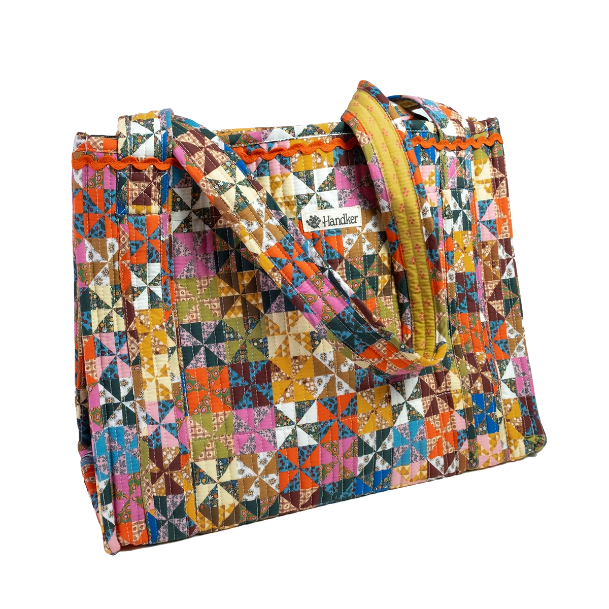 A quilted tote bag featuring a vibrant, multicolor geometric patchwork pattern with a mustard yellow zipper and handles, shown on a plain white background.