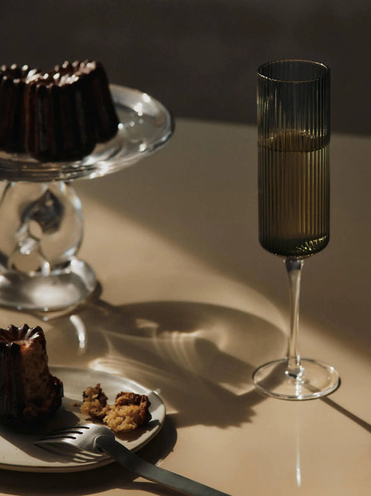 The Ripple Champagne Flutes bring a refined, elongated silhouette to the beloved Ripple series, perfectly suited for sparkling wines. Mouth-blown into the mould, each glass features the signature rippled surface that adds texture and a sense of movement. Their tall, slender shape enhances bubbles and aroma, making any toast feel celebratory. Canele and champagne
