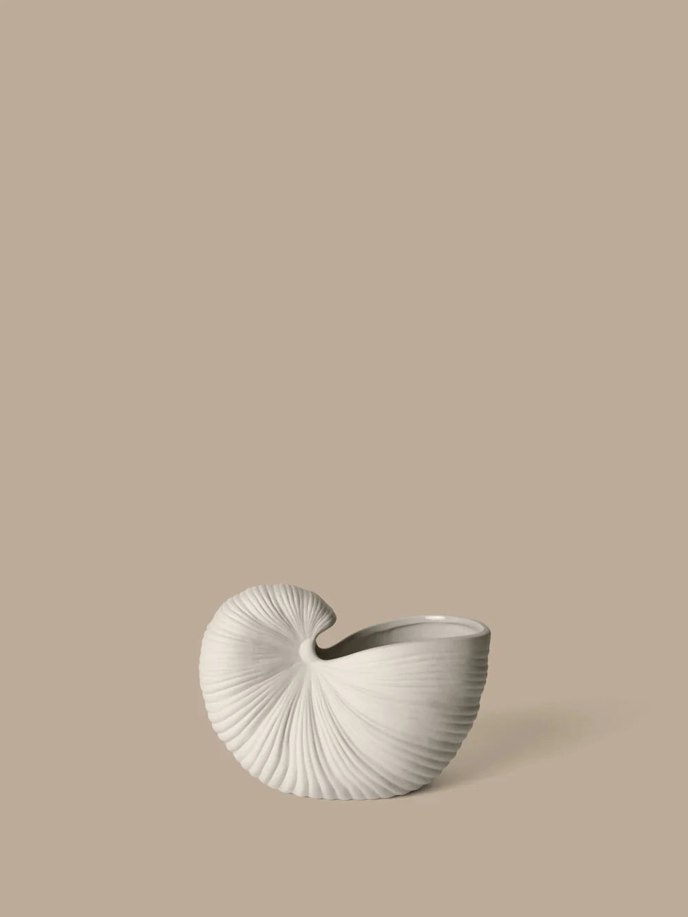 A sculptural, shell-shaped ceramic planter in a textured off-white glaze, set against a solid warm beige background.