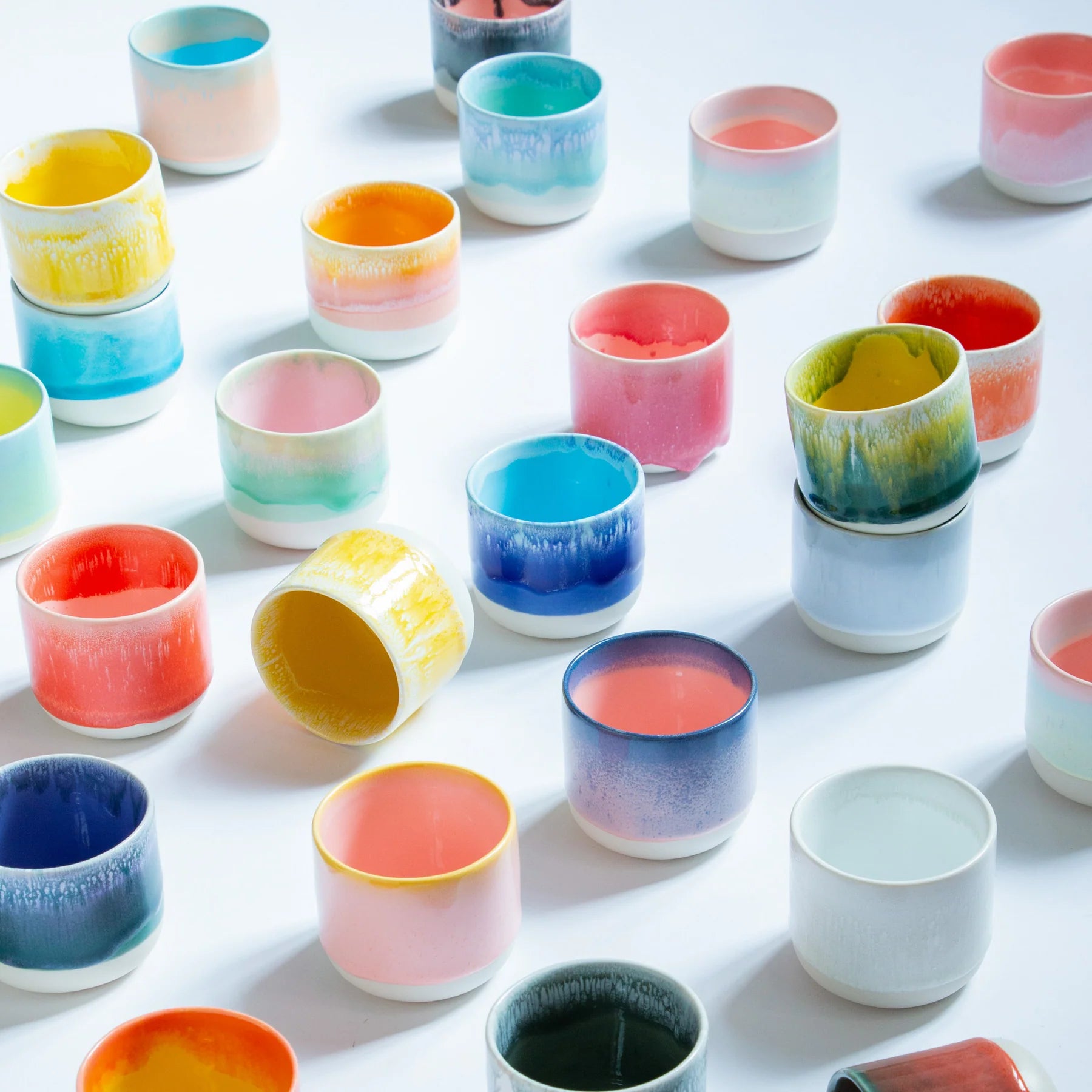 Colorful ceramic cups arranged on a white surface