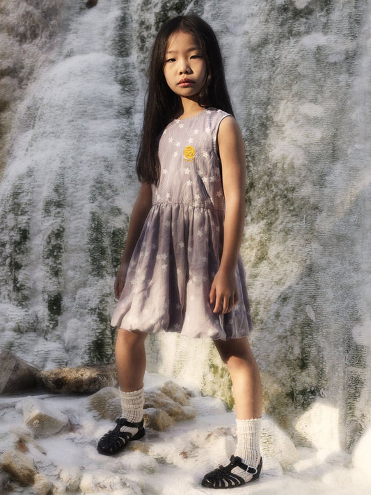 Sleeveless dress made from 100% lyocell. Features the Starfall print, a gathered skirt with bubble hem, and a small embroidered planet patch. Back neck keyhole with snap closure.