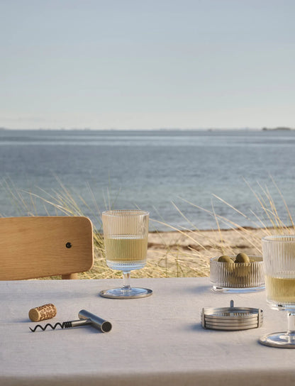 Table setting with glasses and a bottle by a scenic waterfront.