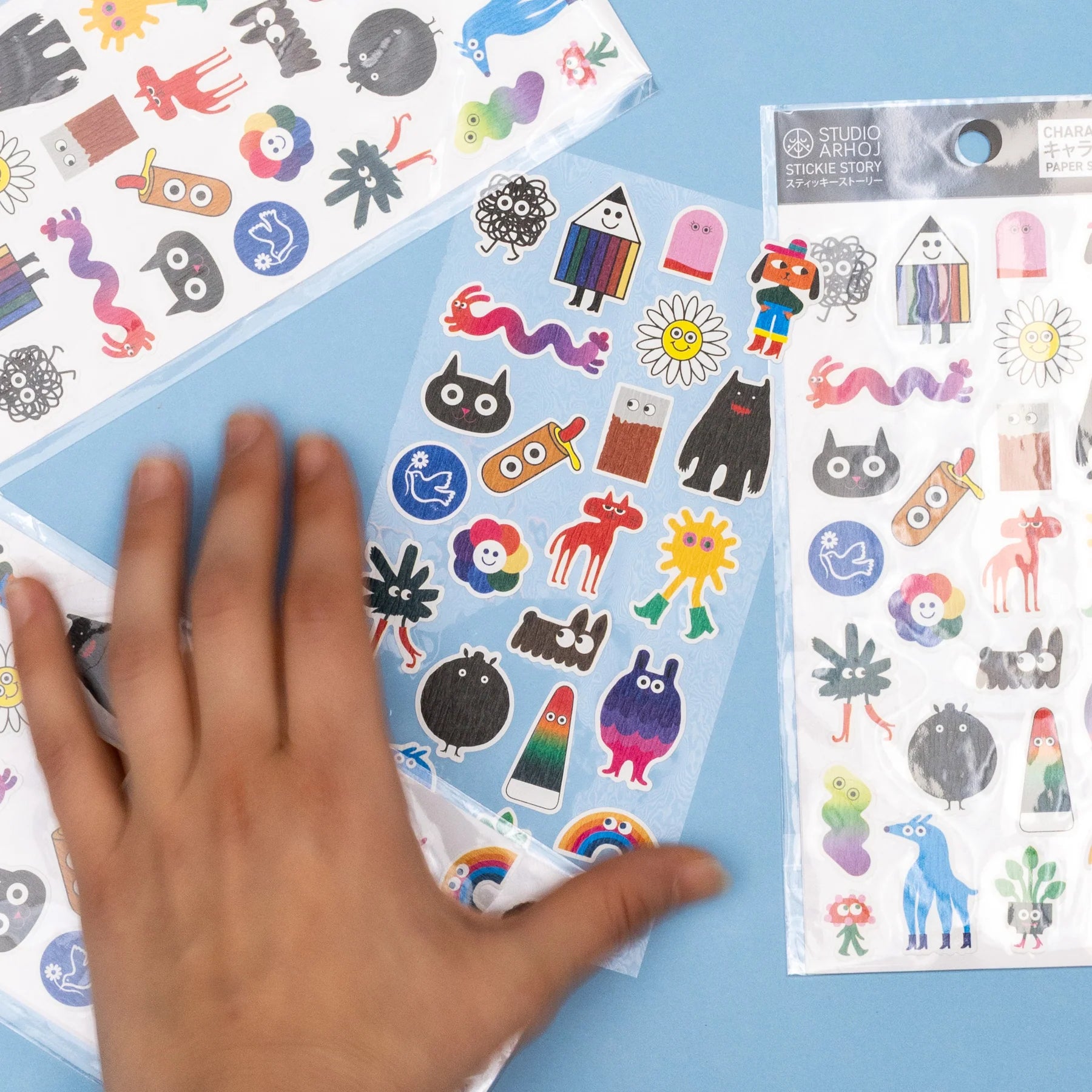 Colorful sticker sheets with a hand reaching for one of them on a blue background