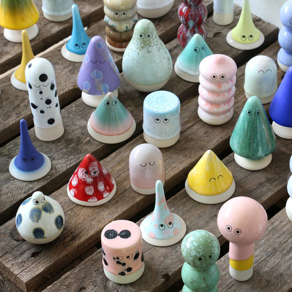 Collection of colorful ceramic figures with facial expressions on a wooden surface