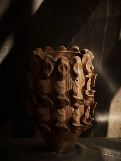 Wooden vase with intricate carvings on a dark background