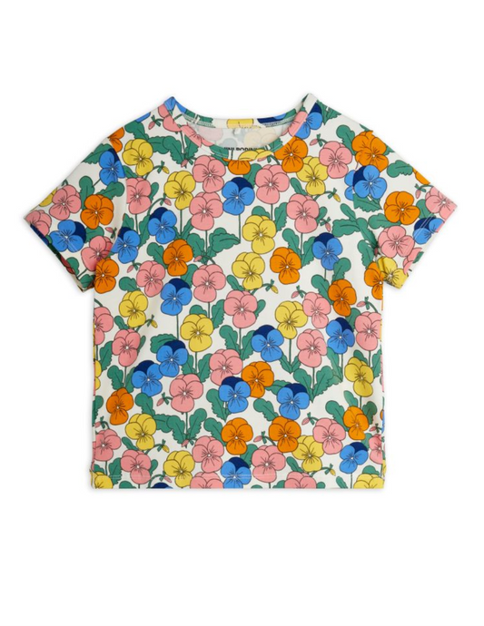 A short-sleeve crewneck t-shirt featuring a colorful floral print of pansies in pink, blue, yellow, and orange with green leaves on a white background.
