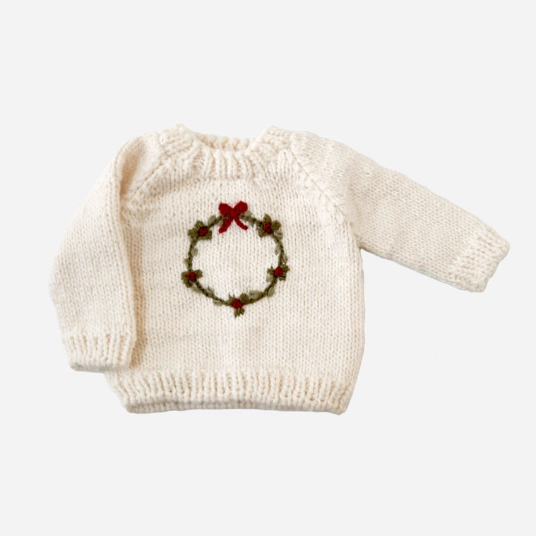Deck the halls with our festive Wreath sweater. This Cream sweater features a hand-embroidered Moss wreath with Red berries and a simple bow. Pair with the Present hat&nbsp;