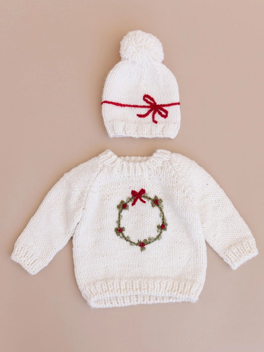 Deck the halls with our festive Wreath sweater. This Cream sweater features a hand-embroidered Moss wreath with Red berries and a simple bow. Pair with the Present hat&nbsp;