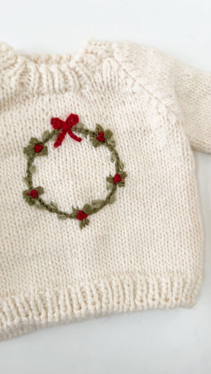 Deck the halls with our festive Wreath sweater. This Cream sweater features a hand-embroidered Moss wreath with Red berries and a simple bow. Pair with the Present hat&nbsp;