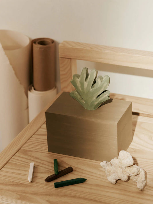 Small green wooden plant on a wooden block with natural light and minimal background