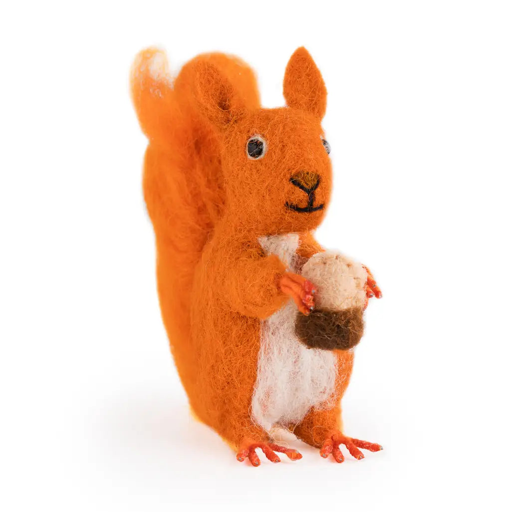 Felted red squirrel toy holding a pine cone on a white background