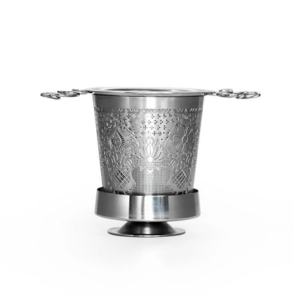 Metallic tea infuser with intricate design on a white background