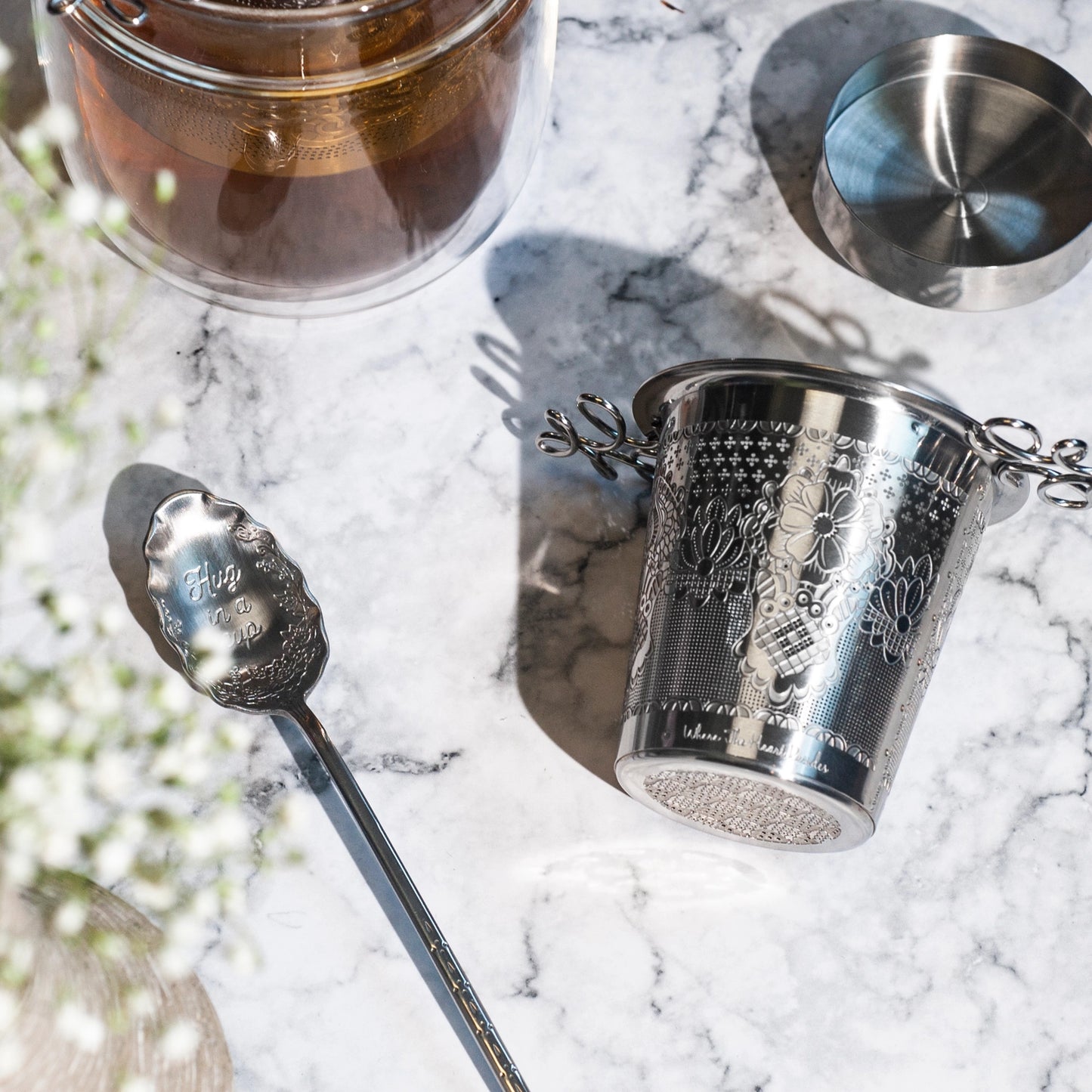 Silver tea cup and spoon on a marble surface with a blurred natural background