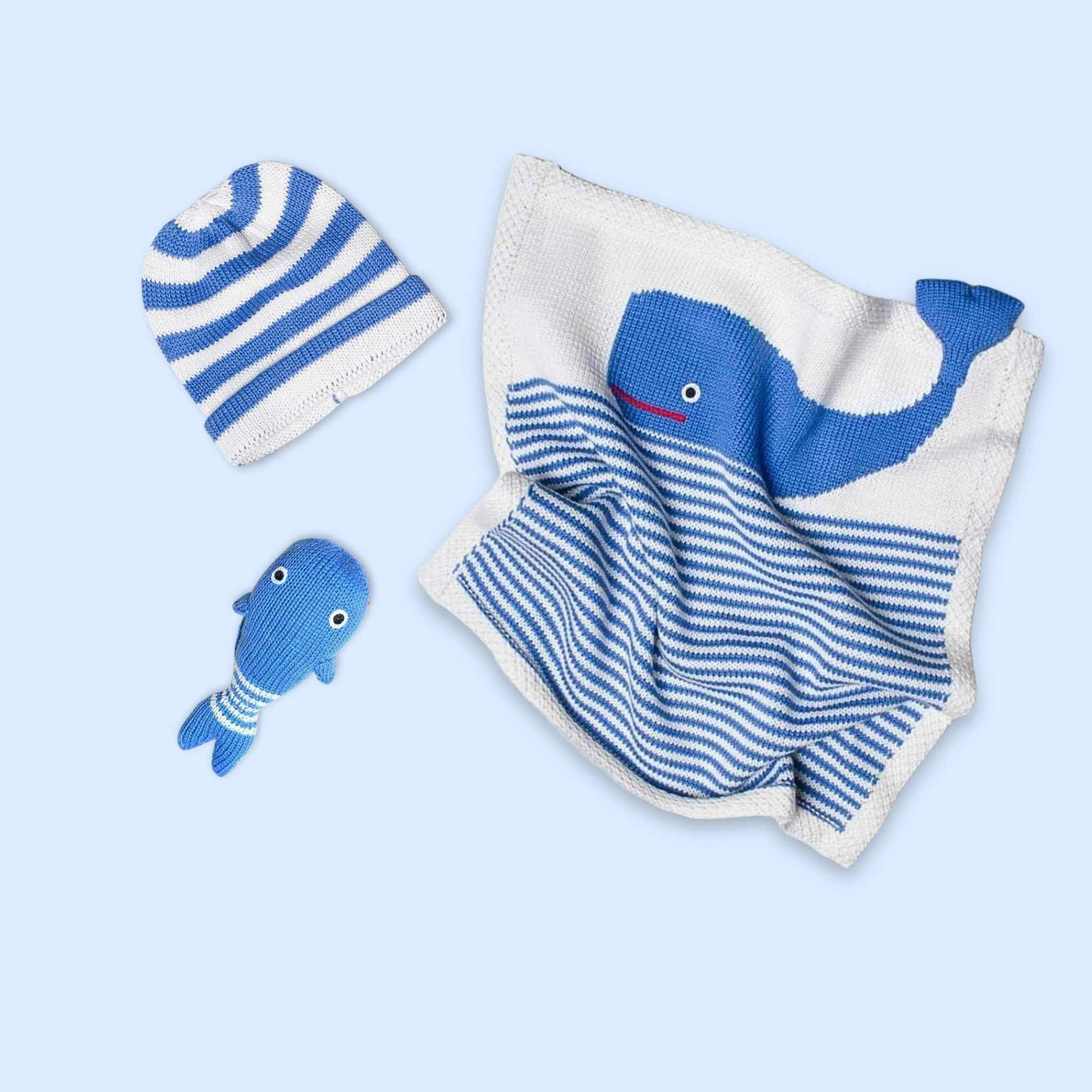 Baby clothing set with striped hat, blanket, and toy on a light blue background