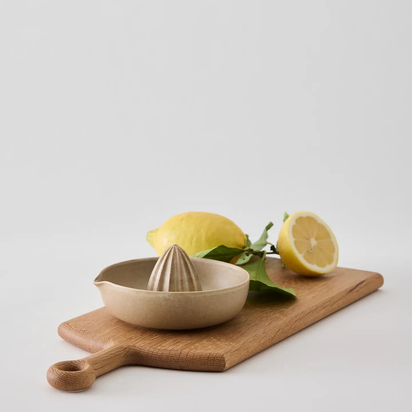 Ceramic lemon squeezer on a wooden cutting board with lemons on a light background