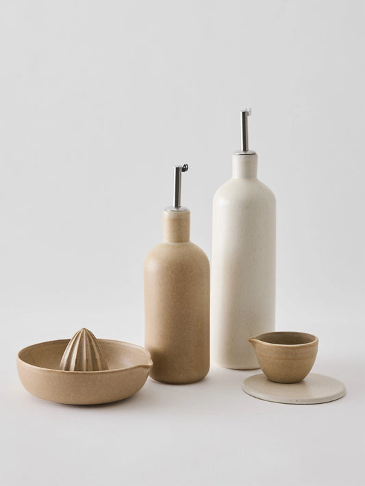Oil bottle in cream-coloured stoneware with a narrow metal spout that provides a smooth and controlled flow. The spout is fitted with a silicone cork to ensure an airtight seal when pouring. Perfect for oil, vinegar, or other liquid condiments in the kitchen. Available in two sizes and part of the Palermo stoneware series. Swedish design from Tell Me More and sold at Huset Shop in Venice Beach. The Scandinavian homeware fits any aesthetic. 