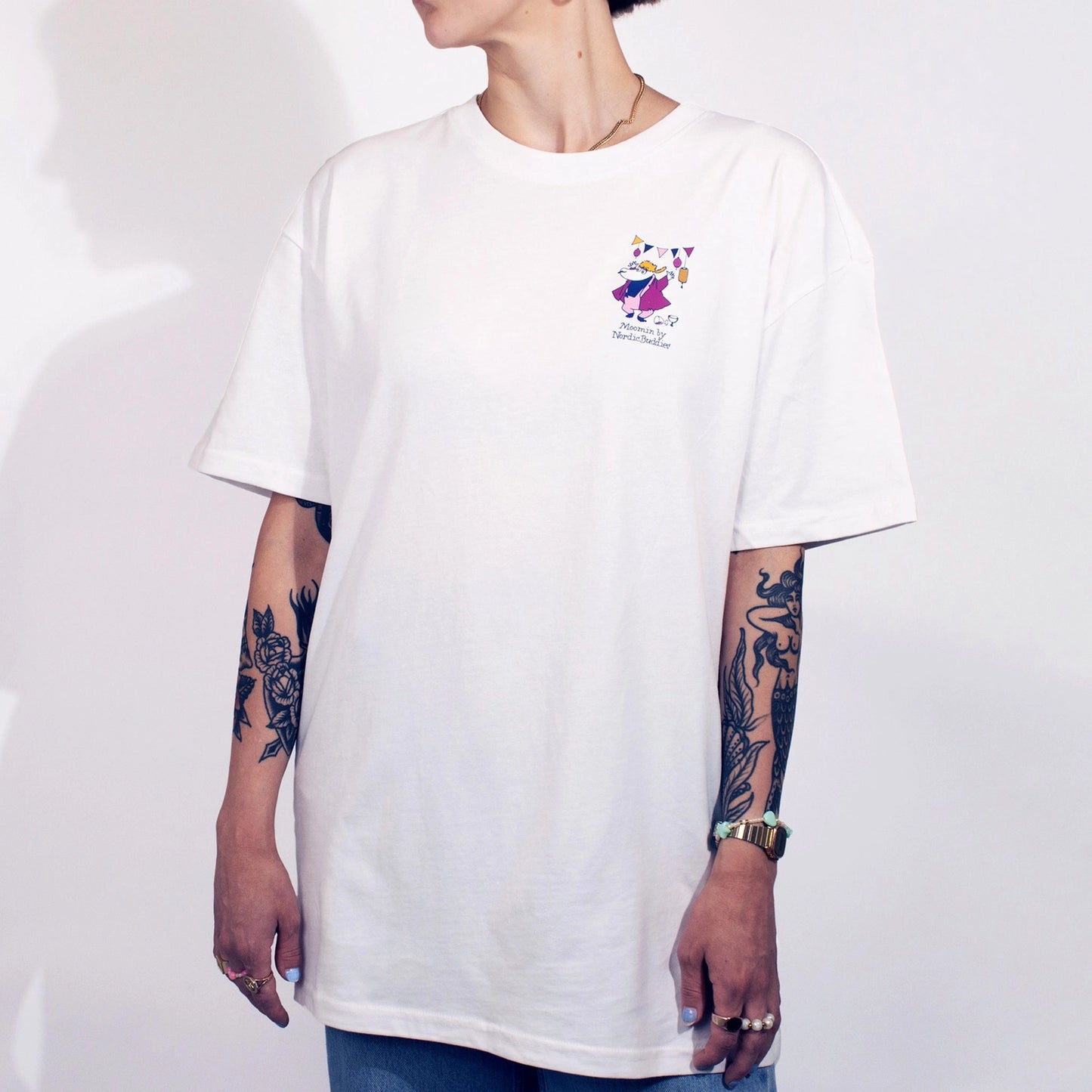 Person wearing a white t-shirt with a small logo on a plain background