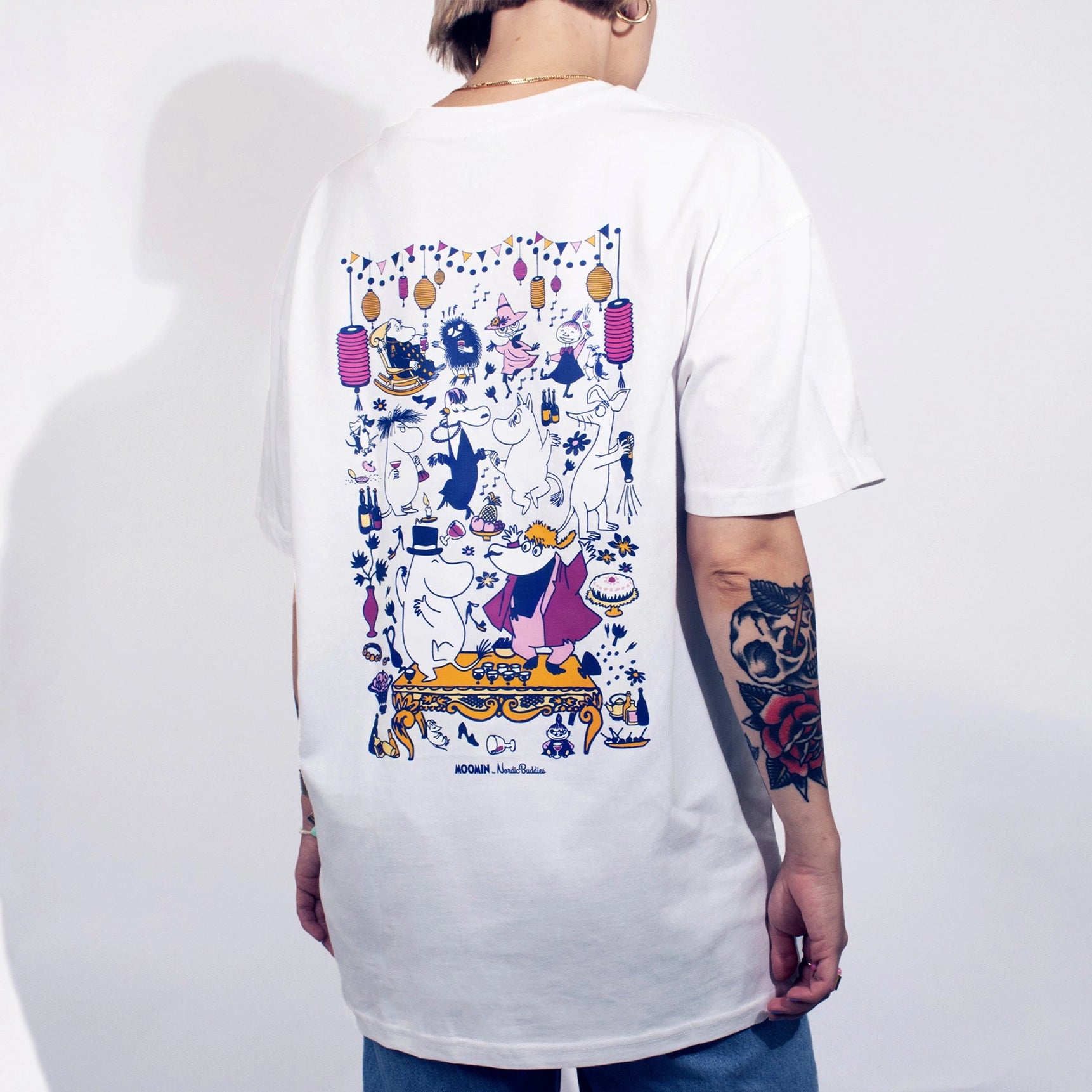 Person wearing a white t-shirt with colorful graphic design on a plain background