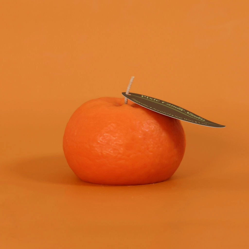 Orange candle with a leaf on an orange background
