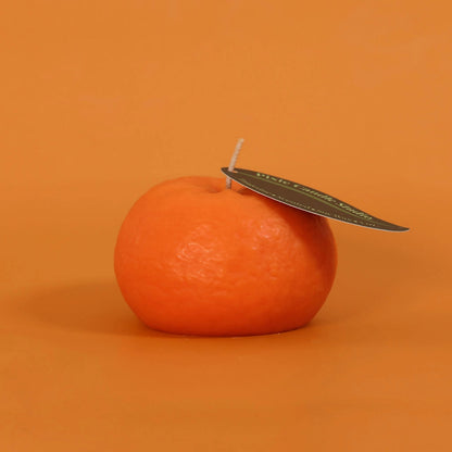 Orange candle with a leaf on an orange background
