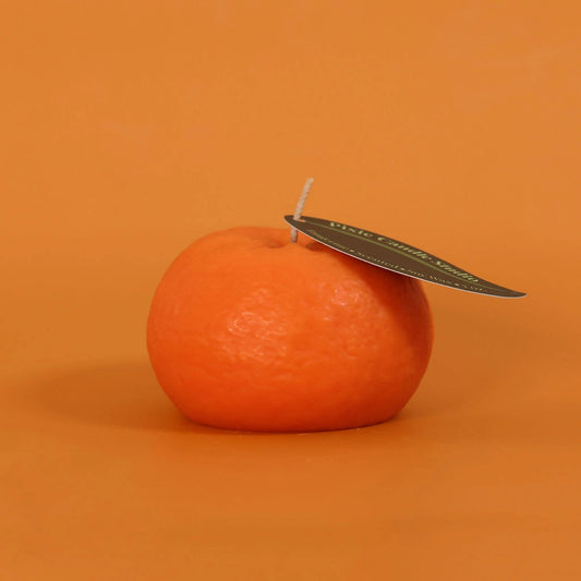 Orange candle with a leaf on an orange background